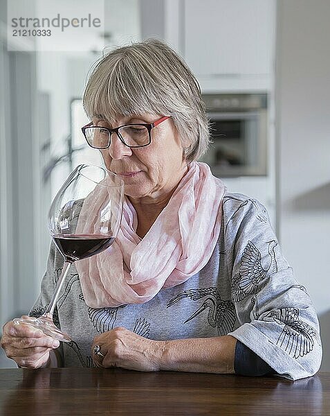 Seniorin trinkt wein an einem Tisch