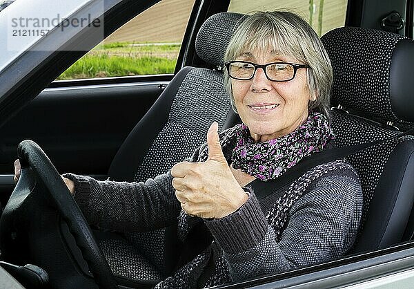 Seniorin im Auto zeigt Daumen nach oben