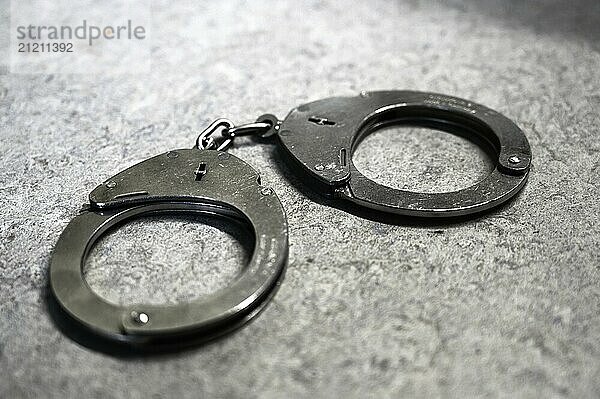 Silver handcuffs on a grey background symbolise criminality