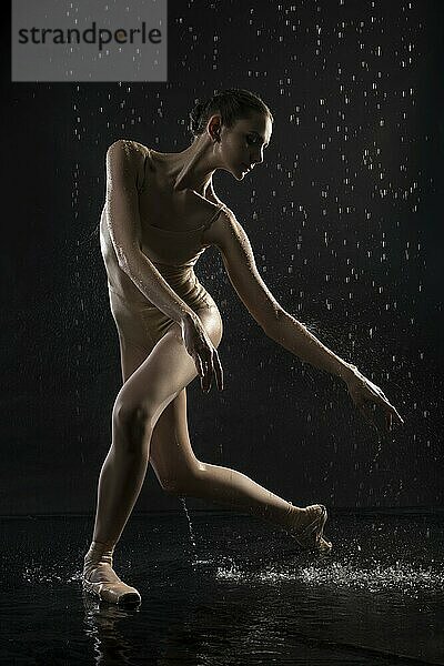 Ballerina wearing beige underwear dancing barefoot view under water in the dark room