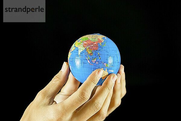 Male hands holding the Earth globe on black background