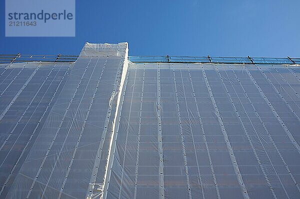 Shielding of a building by a tarpaulin attached to scaffolding against a clear blue sky  Bergen  Vestland  Norway  Europe