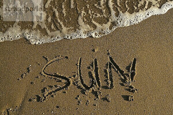 Turkish sea shore with word sun written on the sand washed by waves high angle close up shot