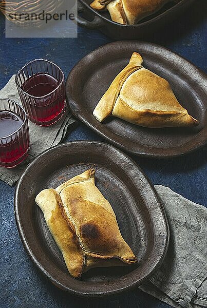 Food  Food  Tipical Chilean baked empanadas de pino y napolitano on clay plates with wine. Dish and drink on 18 September party Independence day Chile  blue background