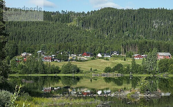 Typical red and white houses in norway with reflection in the water of the leira fjord in middle norway