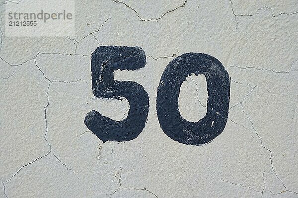 Dark blue number 50 painted on a bright  cracked white wall  Sandnes  Fylke Rogaland  Norway  Europe