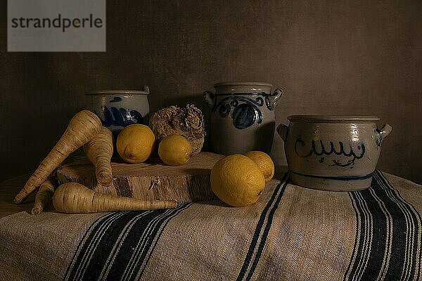 A still life of Cologne pots of lemon  parsnip and celeriac on a canvas with a brown background