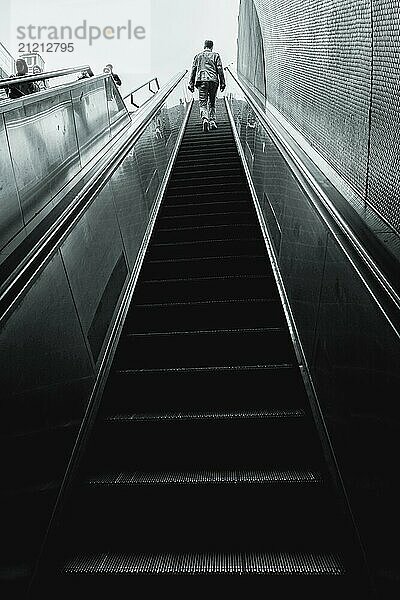 Ein Mann steigt eine lange  moderne Rolltreppe hinauf  die in monochromen Farbtönen gehalten ist  Schlossplatz  Stuttgart  Deutschland  Europa