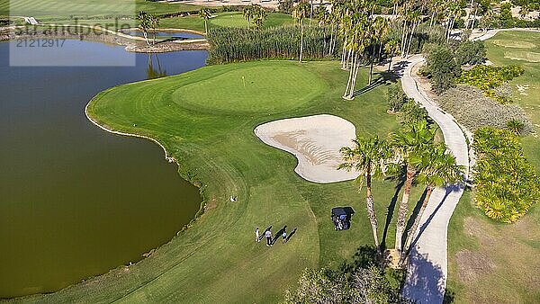 Views of a huge and luxurious green golf course with a natural pool and paths