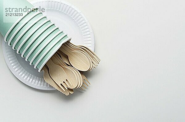 Wooden single use kitchenware and paper cups and plates on white. Top view