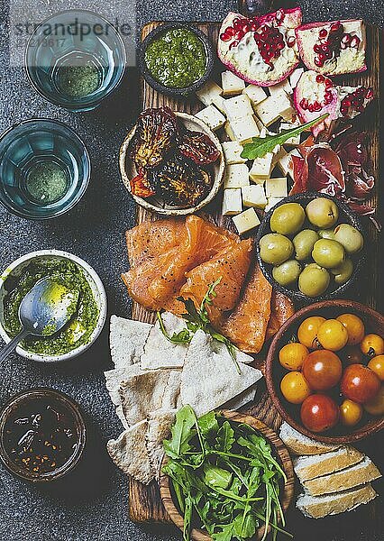 Food  Food  Antipasto. Wine set appetizer. Ham serrano  smoked salmon  dried and fresh tomatoes olive cheese  wine on board. Top view  gray cncrete background