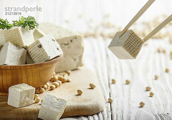 Soy Bean curd tofu in wooden bowl on white wooden kitchen table. Non-dairy alternative substitute for cheese. Place for text