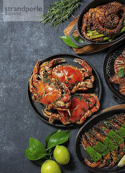 Food  Set of Seafood Dishes. Crabs  octopus  squids and tiger shrimps on cast iron pans and plates on a black background. Top view. Copy space for text