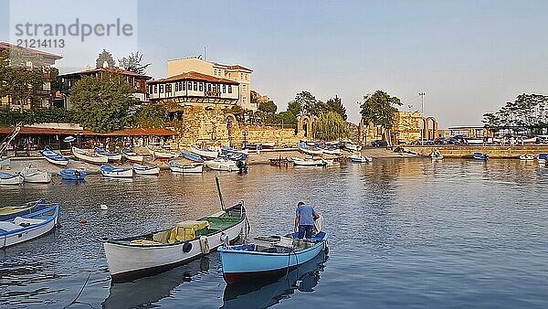 Heitere Hafenszene im warmen Licht des Sonnenuntergangs  zahlreiche kleine Boote treiben auf dem ruhigen Wasser. Traditionelle historische Gebäude und antike Ruinen in der Altstadt von Nessebar in Bulgarien  UNESCO Welterbe