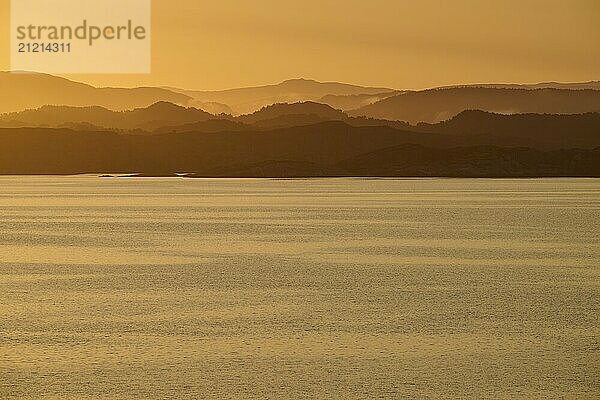 Calm atmosphere over the sea  hills and an orange sunrise  autumn  Bergen  North Sea  Norway  Europe