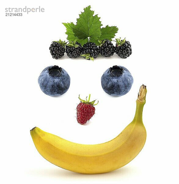 Smile face made of fruits  banana with raspberries and blueberries isolated on white background