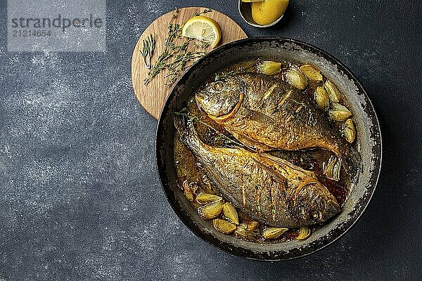 Food  Food  Baked sea bream or dorada with onion and herbs in pan on dark background