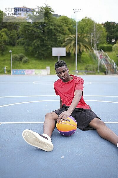 Portrait of an african sportive basketball player sitting in an outdoor court