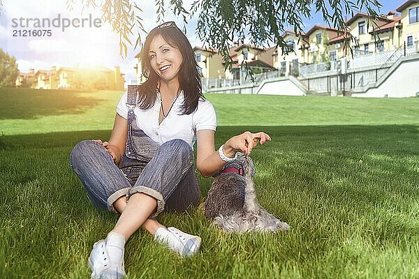 Caucasian joyful woman playing with her beloved dog in the park. The concept of love for animals. best friends. Dog breed Schnauzer