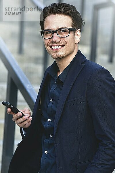 Happy caucasian businessman in glasses dressed at classic wear standing at the street