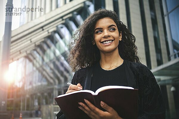 Self employed Mixed-race female entrepreneur busy writing in her notebook