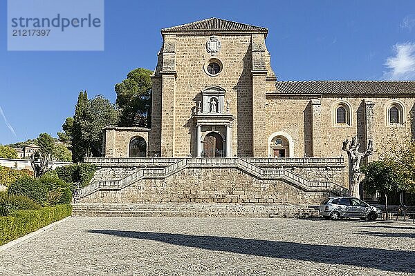 Frontansicht einer historischen Kirche mit Bäumen und klarem Himmel im Hintergrund  Granada