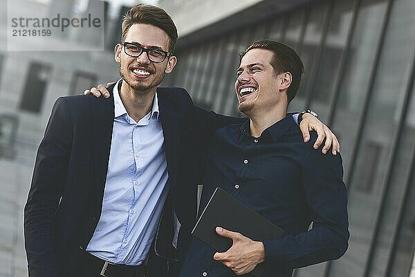 Two smiling colleagues speaking and having fun at street