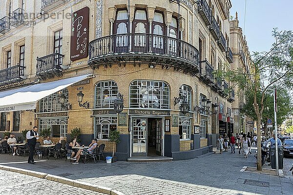 Menschen sitzen in einem Straßencafé vor einem historischen Gebäude in städtischer Umgebung  Sevilla