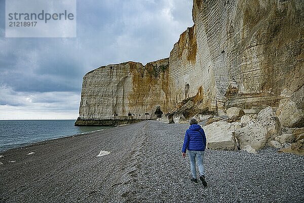 Etretat  france  23-04-2024  woman walking on the beach at the famous calck cliffs in normandy france near etretat  view from the beach