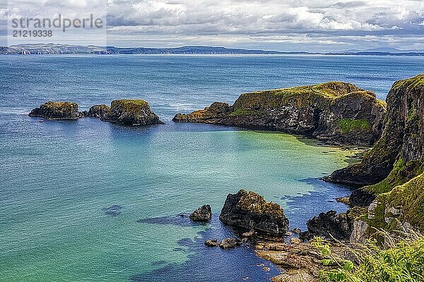 Steile Klippen überblicken das klare blaugrüne Meer unter dramatischem Himmel  County Antrim Coast