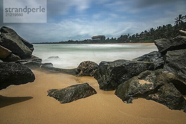 Strand  mit Lavafelsen und Vegetation  Blick auf das Meer am Abend bei Sonnenuntergang. Landschaft mit Wolken in Induruwa  Bentota Beach  Sri Lanka  Indien  Asien