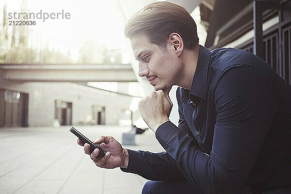 Smiling businessman use a smartphone at street