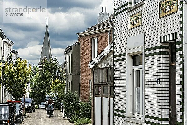 Uccle  Brüssel  Belgien  14.06.2019  Mann mit Fahrrad fährt die kurvige Saint Job Straße hinauf mit Blick auf den Kirchturm  Europa