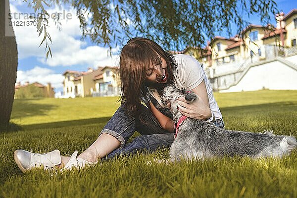 Caucasian joyful woman playing with her beloved dog in the park. The concept of love for animals. best friends. Dog breed Schnauzer