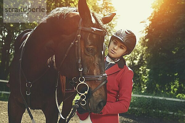 A young girl talking and takes care of her horse. She loves the animals and joyfully spends her time in their environment