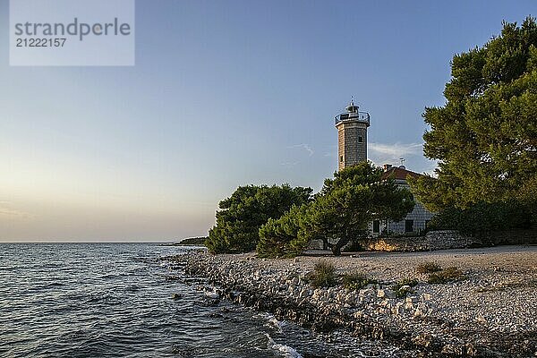 Beautiful sunset in a landscape on a rocky coast with a prominent lighthouse and pine forest. View over the coast to the building  on the Mediterranean Sea  Vir  Dalmatia  Croatia  Adriatic Sea  Europe