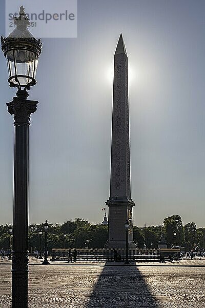 Ein Obelisk erhebt sich hinter einer Laterne  Sonnenlicht verstärkt die Silhouetten  Paris