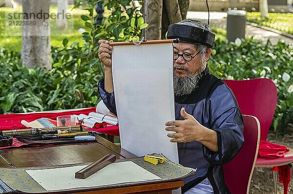 HANOI  VIETNAM  14. NOVEMBER: Alter vietnamesischer Mann in Nationaltracht schreibt Hieroglyphen auf altem Papier auf der Straße am 13. November 2016 in Hanoi  Vietnam  Asien