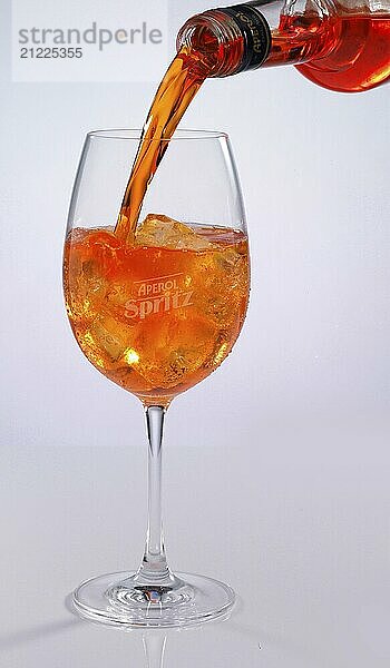 Aperol is poured into a glass against a white background