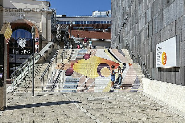 Bunte Kunstinstallation auf Treppen  von Menschen belebt  in einer urbanen Umgebung  Wien