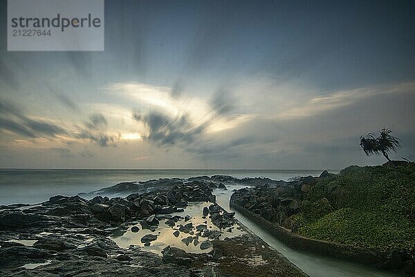 Strand  mit Lavafelsen und Vegetation  Blick auf das Meer am Abend bei Sonnenuntergang. Landschaft mit Wolken in Induruwa  Bentota Beach  Sri Lanka  Indien  Asien