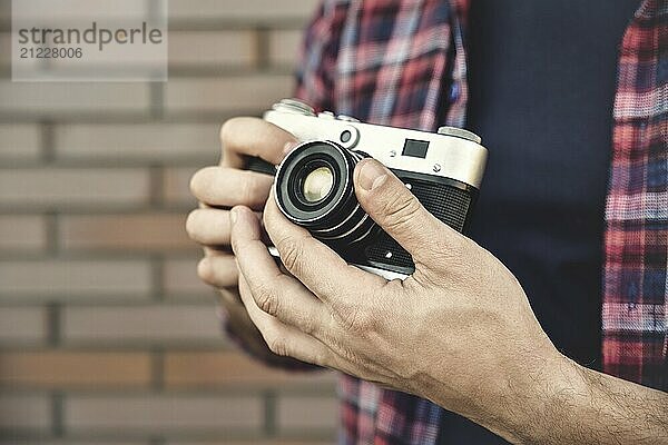 Close up Foto Mann mit Retro Foto Kamera Mode Reisen Lifestyle im Freien  während stehend gegen Backsteinmauer Hintergrund