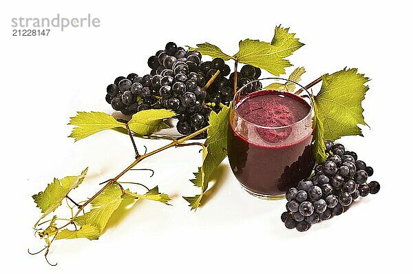 Freshly pressed red grape juice with vine leaves on a white background