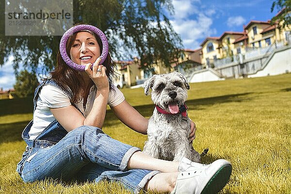 Caucasian joyful woman playing with her beloved dog in the park. The concept of love for animals. best friends. Dog breed Schnauzer