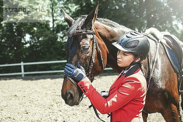 A young girl talking and takes care of her horse. She loves the animals and joyfully spends her time in their environment