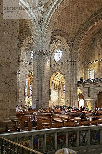 Innenansicht einer Kirche mit hohen Wänden und Besuchern in Sitzreihen  Paris