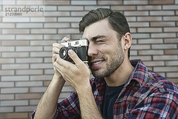 Mann mit Retro Fotokamera Mode Reisen Lifestyle im Freien  während stehend gegen Backsteinmauer Hintergrund