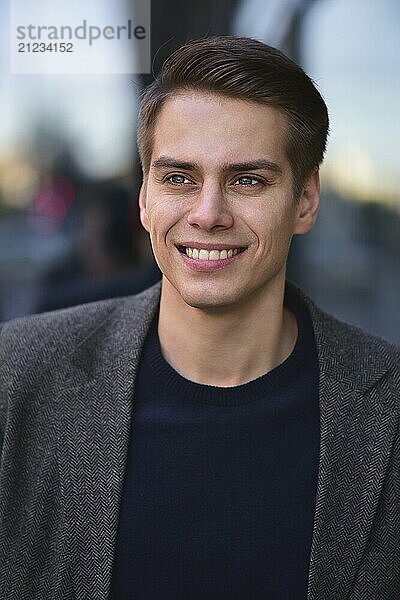 Trendy handsome happy man stay at street in gray coat and blue sweater