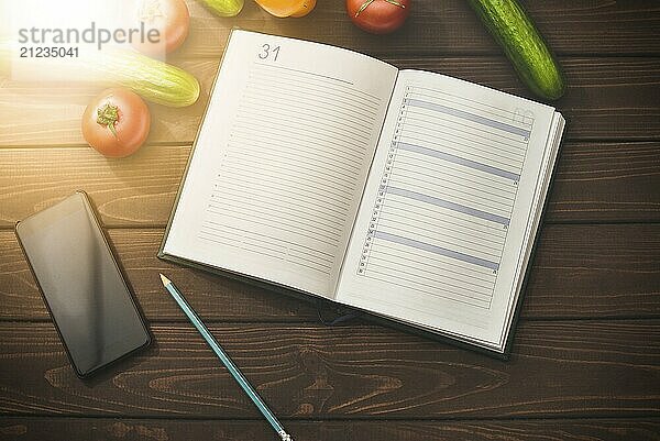 Dieting concept with a smartphone and a notepad and pen surrounded by lots of healthy fruit and vegetables