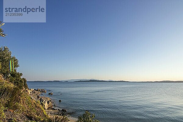 View from a hill with olive trees to the sunset and the sea. Evening atmosphere of a Mediterranean landscape on the beach and coast of Ouranoupoli  Thessaloniki  Central Macedonia  Greece  Europe